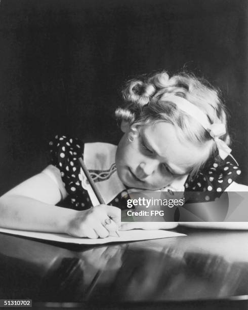 Curly-haired blonde girl commits her thoughts to paper, circa 1945.