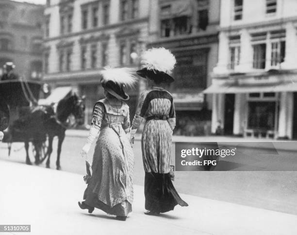 Two fashionably dressed women take a stroll on a city street, 1909.