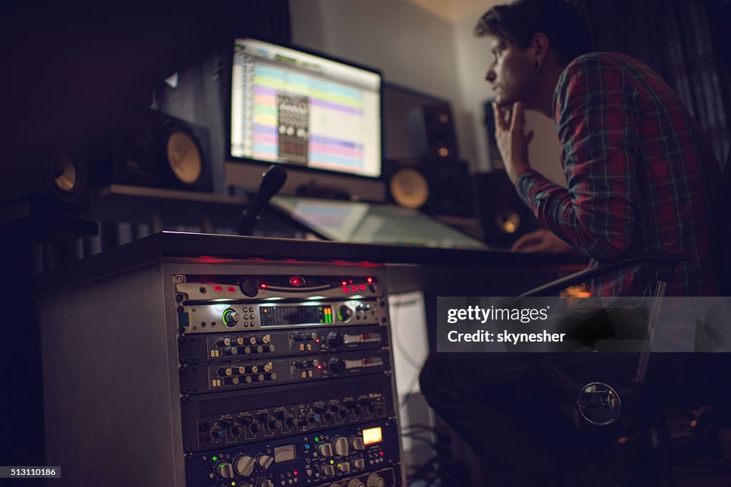 Audio rack in recording studio with producer in the background.