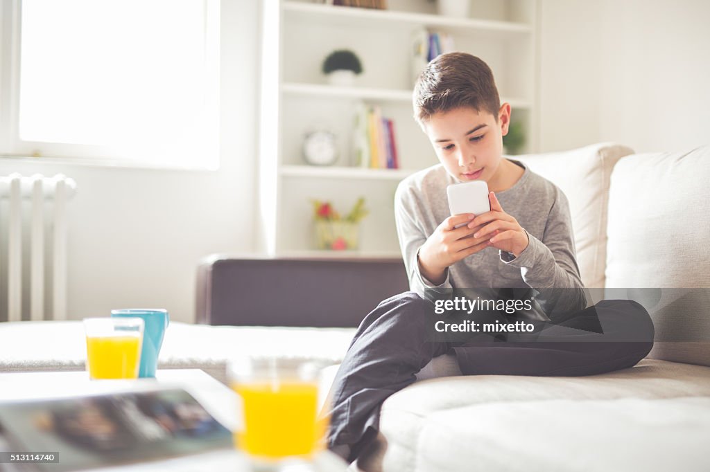 Garçon avec téléphone portable à la maison