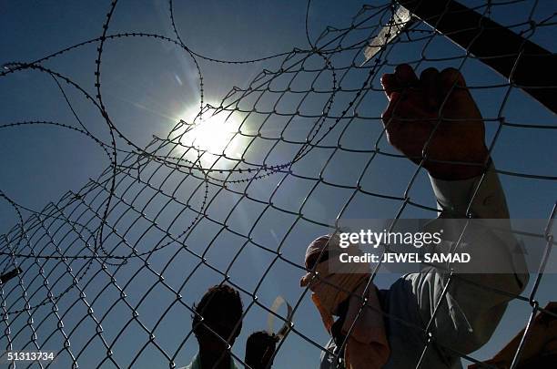 Iraqi detainees watch the release of prisoners leaving the Abu Ghraib jail on the outskirts of Baghdad, 16 September 2004. Some 108 detainees were...
