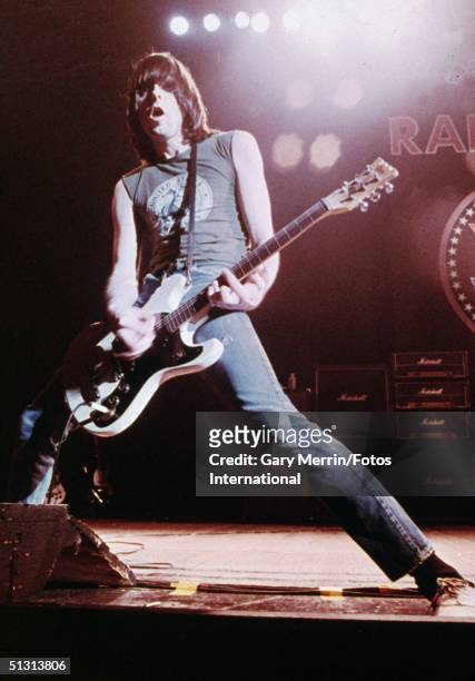 American musician Johnny Ramone performs on guitar with his legs spread wide onstage during a Ramones concert at the Hammersmith Odeon, London,...