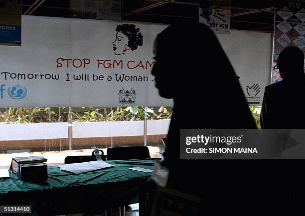 Young woman walks past a campaign banner against female genital mutilation [FGM] at the venue of an International conference, 16 September 2004 in...