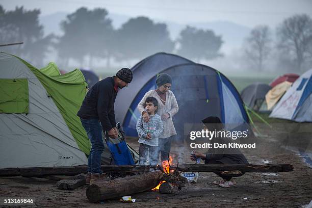 Family warm themselves by a fire in the early morning on the Greek-Macedonia border on March 01, 2016 in Idomeni, Greece. The transit camp has become...