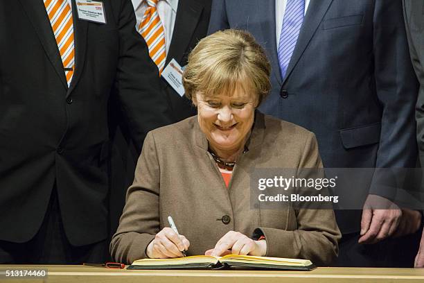 Angela Merkel, Germany's chancellor, signs a book during a Christian Democratic Party local election campaign rally in Volkmarsen, Germany, on...