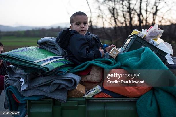 Young boy is pulled along by his father in a wheelie bin towards the Greek-Macedonia border on March 01, 2016 near Idomeni, Greece. The transit camp...