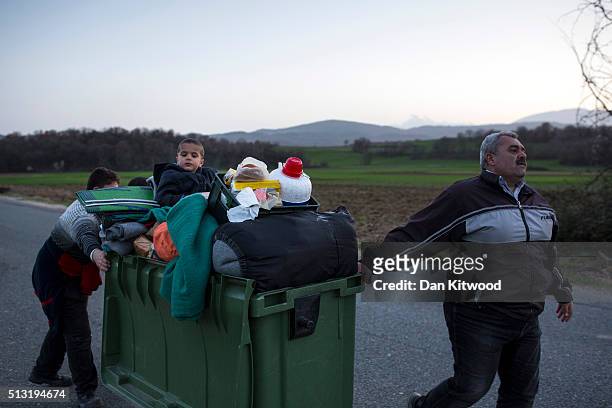Man pulls his belongings and family along in a Wheelie Bin towards the Greek-Macedonia border on March 01, 2016 near Idomeni, Greece. The transit...