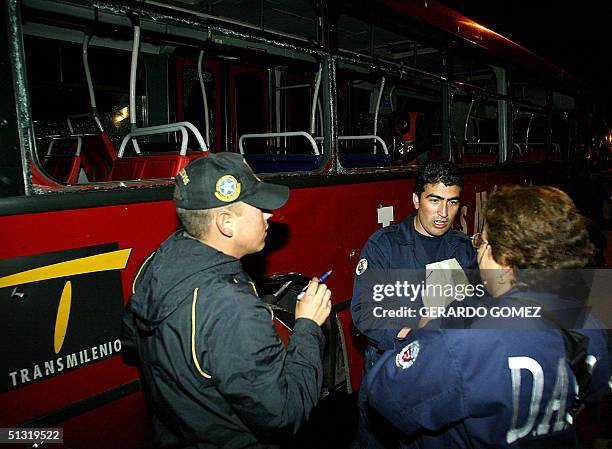 Miembros de la Policia Secreta inspeccionan los danos ocacionados por la explosion de una bomba de bajo poder a un autobus de la compania...