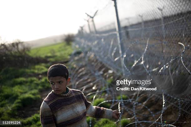 Young refugee boy stands at the wire fence of the Greek-Macedonia border on March 01, 2016 near Idomeni, Greece. The transit camp has become...