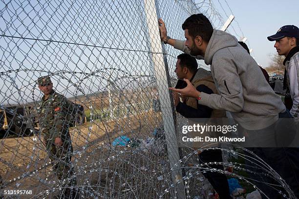 Refugee men talk to a Macedonian soldier at the other side of the fence at the Greek-Macedonia border on March 01, 2016 near Idomeni, Greece. The...