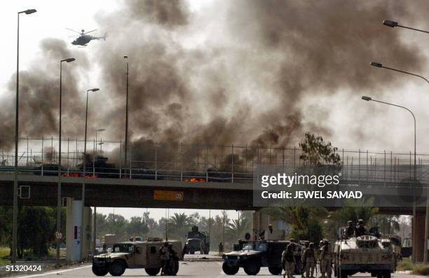 Heavy smoke billows from a burned US Humvee and a civilian car at a bridge that leads to Baghdad's International Airport 18 September 2004. A US...