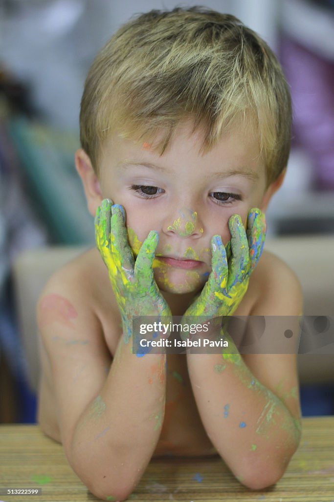 Boy with painted hands holding his face