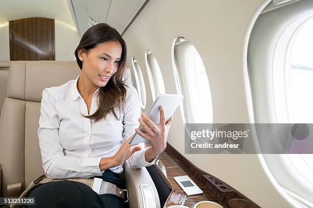 femme profitant de divertissement à bord dans sa tablette informatique - corporate travel photos et images de collection