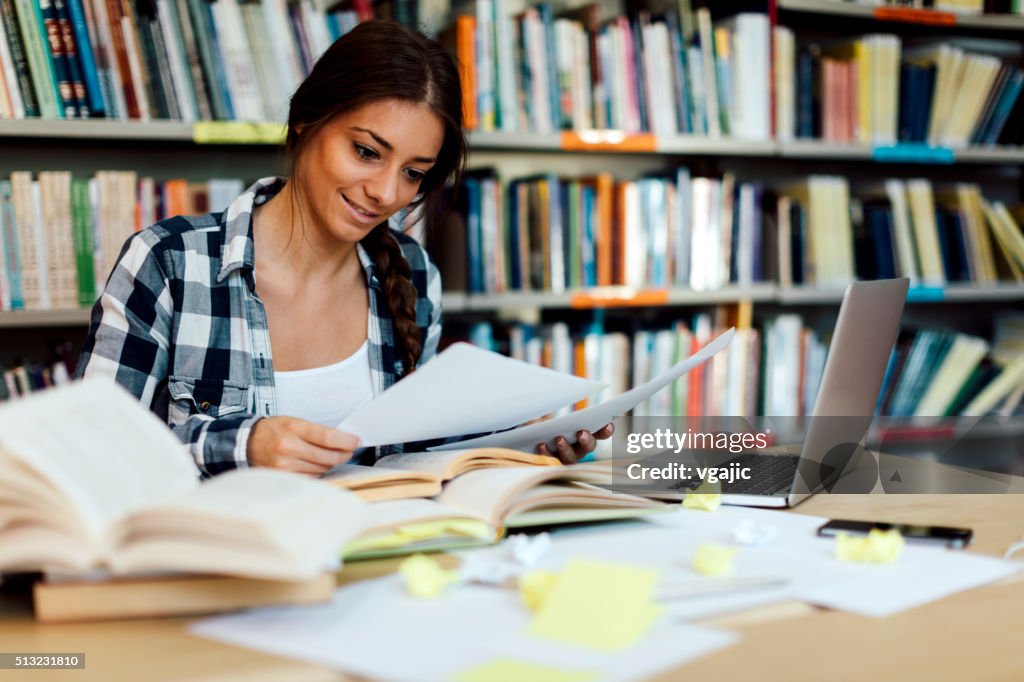 Female student using laptop for taking notes to study