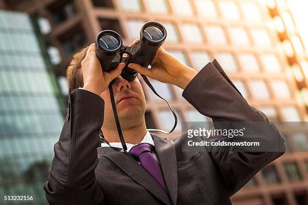 young professional looking through binoculars in business district, london, uk - spy glass businessman stock pictures, royalty-free photos & images