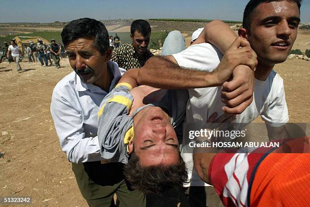 Palestinians carry 19 September 2004 a wounded protestor during a demonstration against the construction of a new section of Israel's "security"...