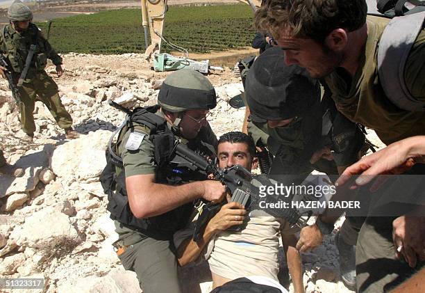 Israeli border guards arrest a Palestinian protestor, 19 September 2004, during a demonstration against the construction of a new section of Israel's...