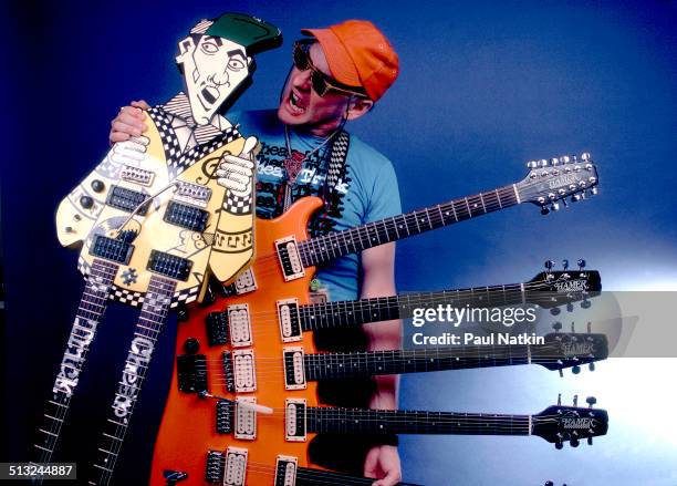 Portrait of American musician Rick Nielsen, of the band Cheap Trick, as he poses with two of his guitars at the Poplar Creek Music Theater, Chicago,...