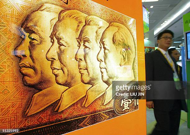 Visitors walks past a poster featuring a one hundred yuan Renminbi bank note at the Hong Kong Financial Services Expo in Shanghai, 20 September 2004....