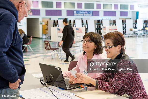 Election volunteers Janice Wolfe, left, and Ly Hom, right, check in voters so they can cast their ballots in the presidential primary at Rachel...