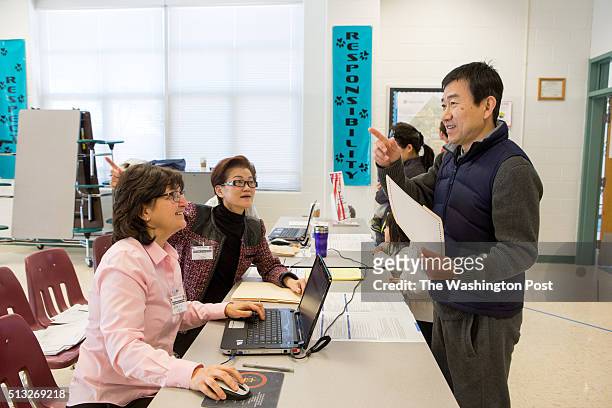 Election volunteer Ly Hom, second from left, directs voter Wentao Yin in Mandarin towards a voting station as fellow volunteer Janice Wolfe, left,...