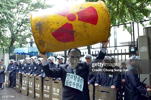 Masked protester holds aloft a mock nuclear waste drum during an an anti-nuclear rally in front of Government House on September 20, 2004 in Seoul,...