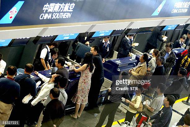 Chinese airline passengers queue up at the newly reopened terminal of Beijing's Capital International Airport, 20 September 2004 after a 14-month...
