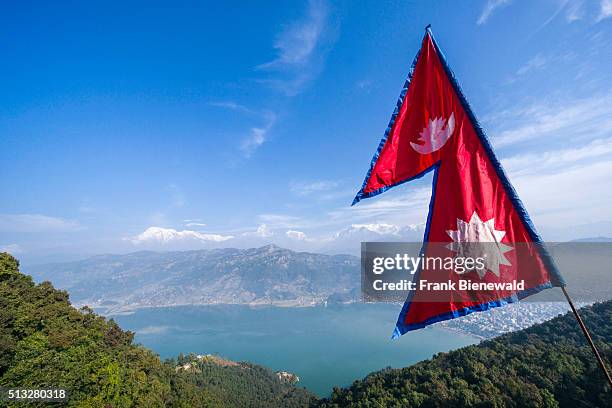 The nepali national flag is weaving high above the Phewa Lake and Pokhara, Annapurna mountains in the distance.