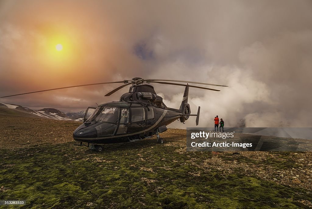 Tourist and helicopter by geothermal area, Iceland