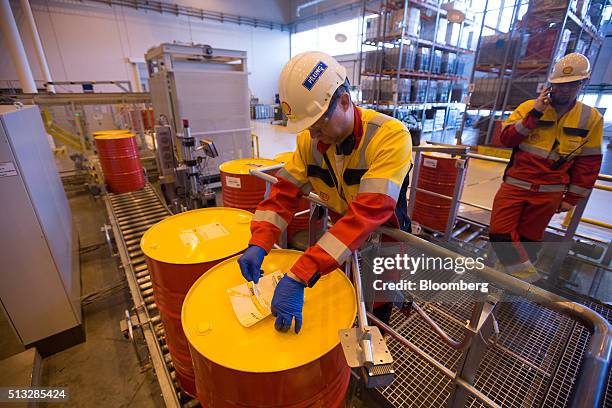 Worker fixes an identifying label to an oil drum containing Omala 52G industrial gear oil at the Royal Dutch Shell Plc lubricants blending plant in...