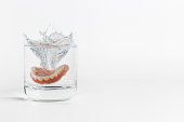 Dentures splashing in glass of water
