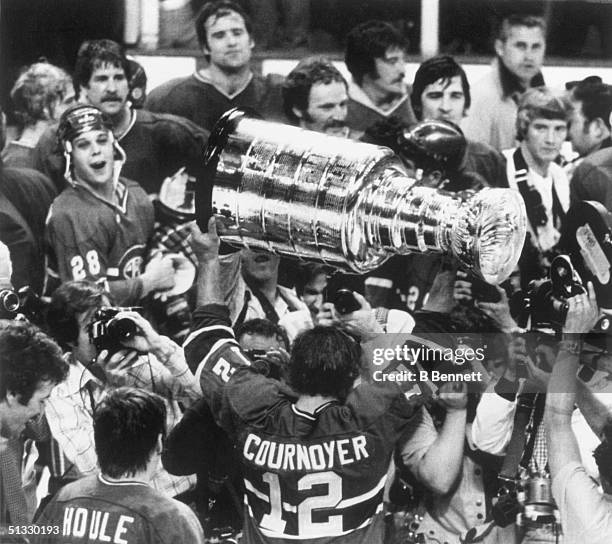Yvan Cournoyer of the Montreal Canadiens, surrounded by his teammates, hoist the Stanley Cup high, after defeating the Boston Bruins 4-1 at the...