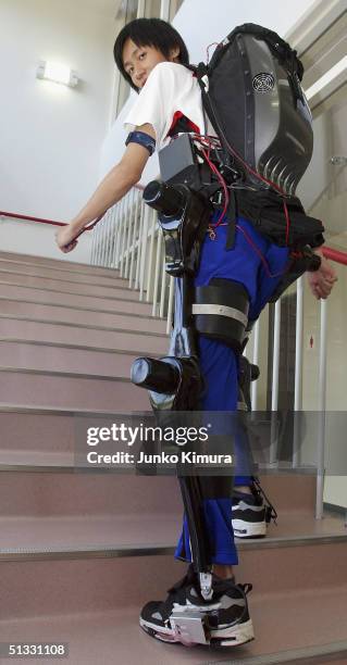 Man walks up stairs demonstrating a prototype of a powered suit, HAL at the University of Tsukuba, on September 21, 2004 in Tsukuba, Ibaraki...