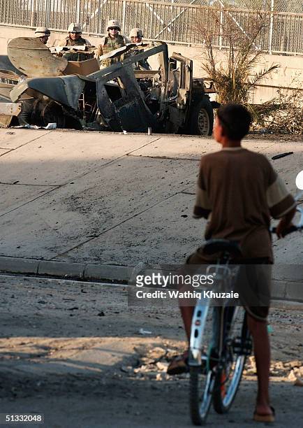 An Iraqi boy looks at U.S. Soldiers at the scene of a car bomb explosion September 21, 2004 in Baghdad, Iraq. A car bomb exploded near a U.S....