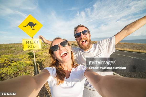 jovem casal tirar uma selfie retrato perto de sinal de aviso de canguru na austrália - free sign imagens e fotografias de stock