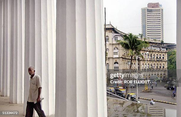 An Indian man walks through the tall white columns of The State Central Library building, built in 1804 by the British, from where a clear view of...