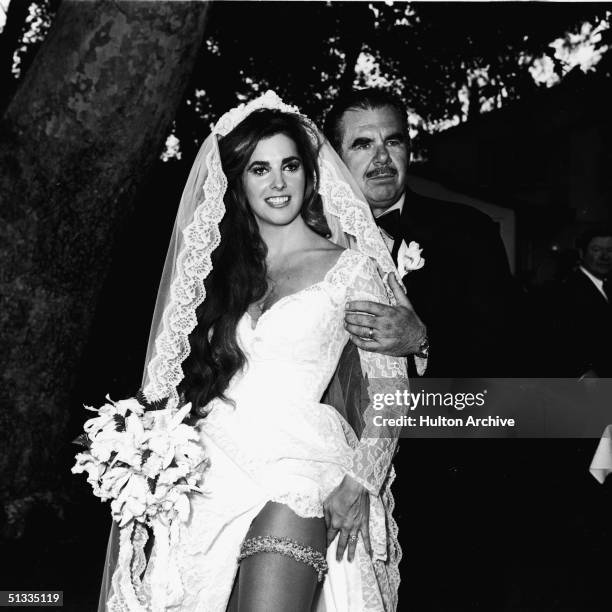 Portrait of American exploitation film director, writer, producer, editor, and actor Russ Meyer with his new wife actress Edy Williams as they pose...