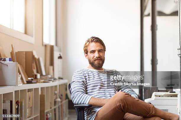 young businessman sitting on chair - lässige kleidung stock-fotos und bilder
