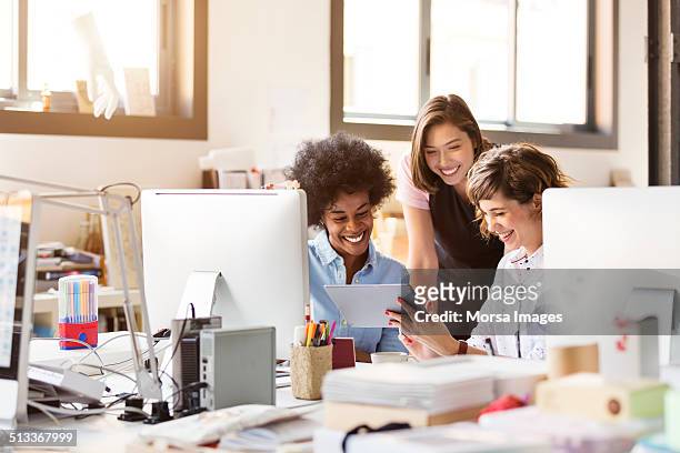 happy businesswomen using digital tablet in office - werkplek stockfoto's en -beelden