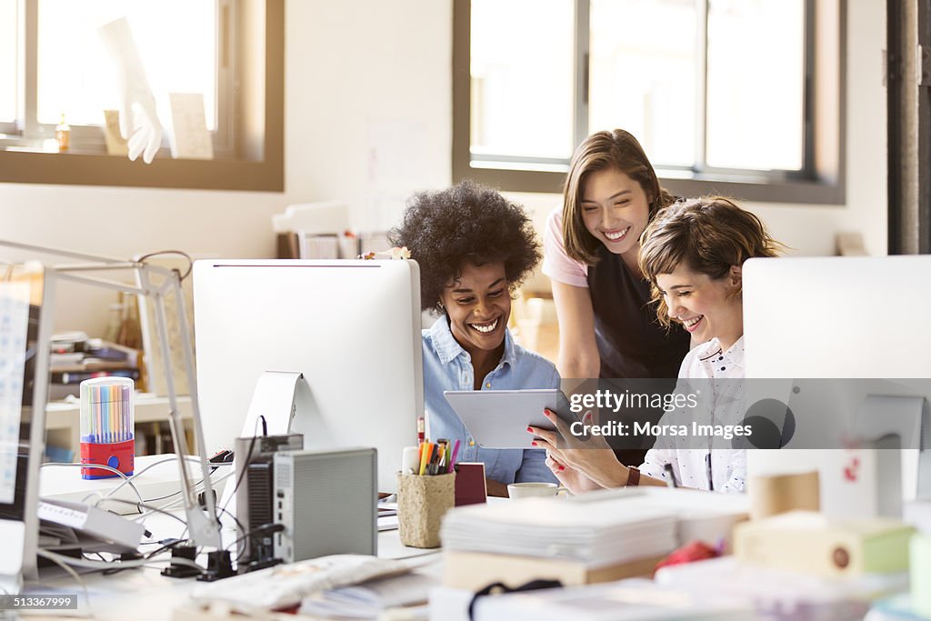 Happy businesswomen using digital tablet in office