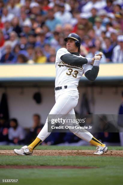 Jose Canseco of the Oakland Athletics watches the flight of the ball as he follows through on a swing during a 1991 MLB season game against the...