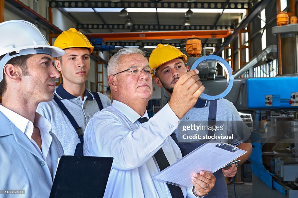 Supervisor and factory workers checking product