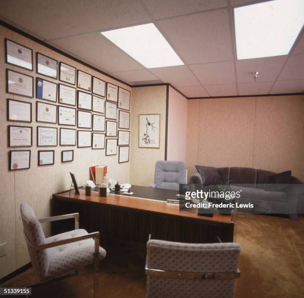 Interior view of the empty office of Alan J. Winters M.D., complete with a desk, chairs, a sofa, and a large number of framed diplomas on the wall,...
