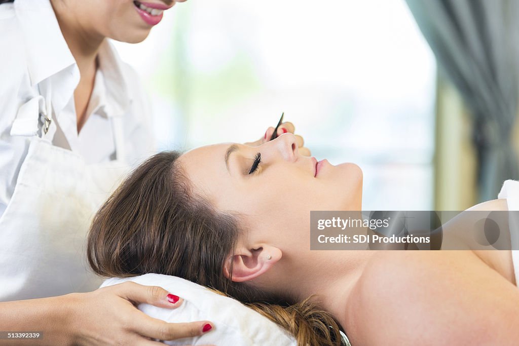 Salon spa stylist applying false eyelash extensions for client