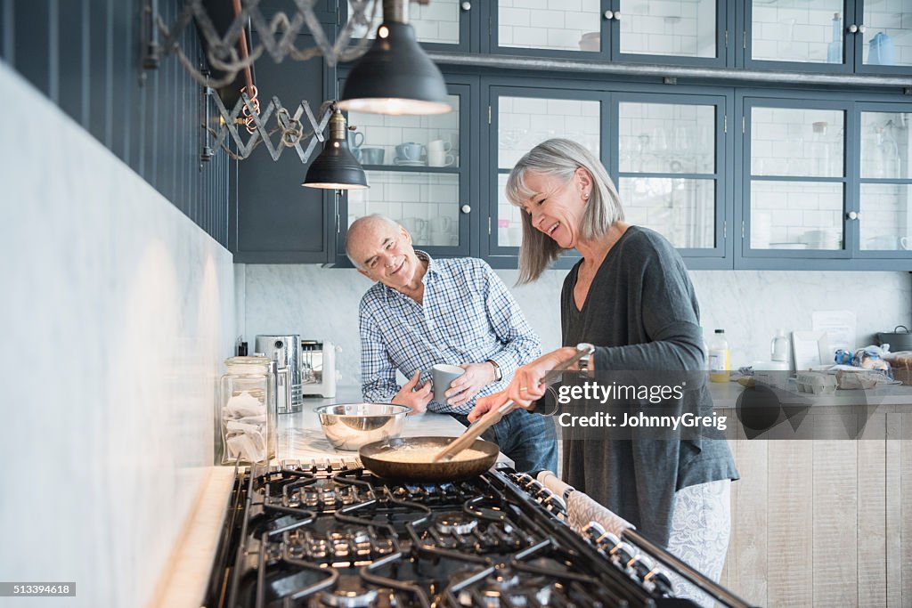 Senior woman cooking dinner talking to her husband