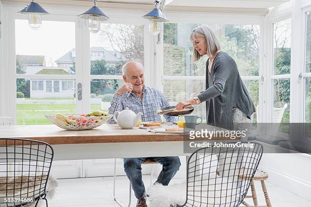 couple senior profiter de déjeuner sur la tableau de dîner - conservatory house photos et images de collection