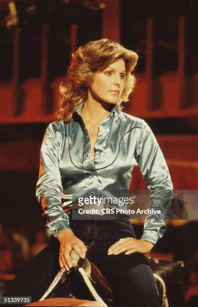 Promotional still from the American television series 'Dallas' shows cast member Priscilla Presley , dressed in a satin shirt and blue jeans, as she...