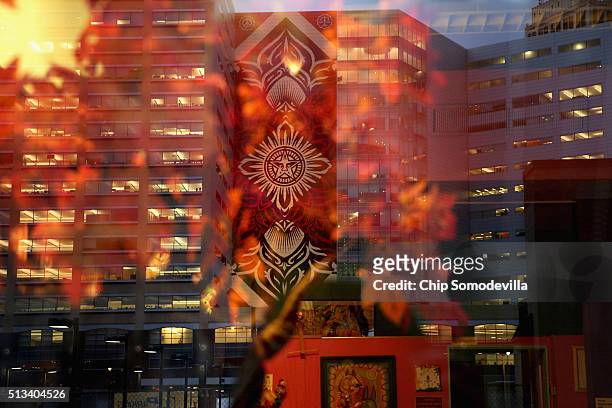 Famous street artist Shepard Fairey's 184-foot by 60-foot mural on the side of the One Campus Martius building is reflected in a window across the...