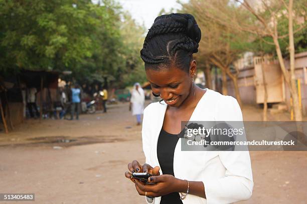 smiling woman with mobile phone - bamako stock-fotos und bilder