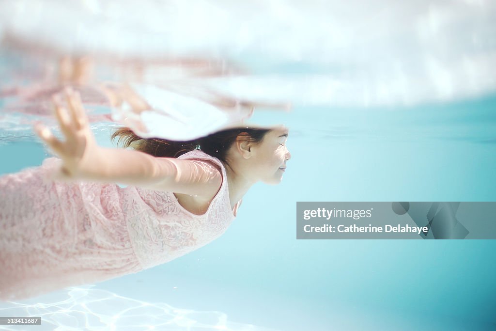 A girl with a dress swimming in a pool